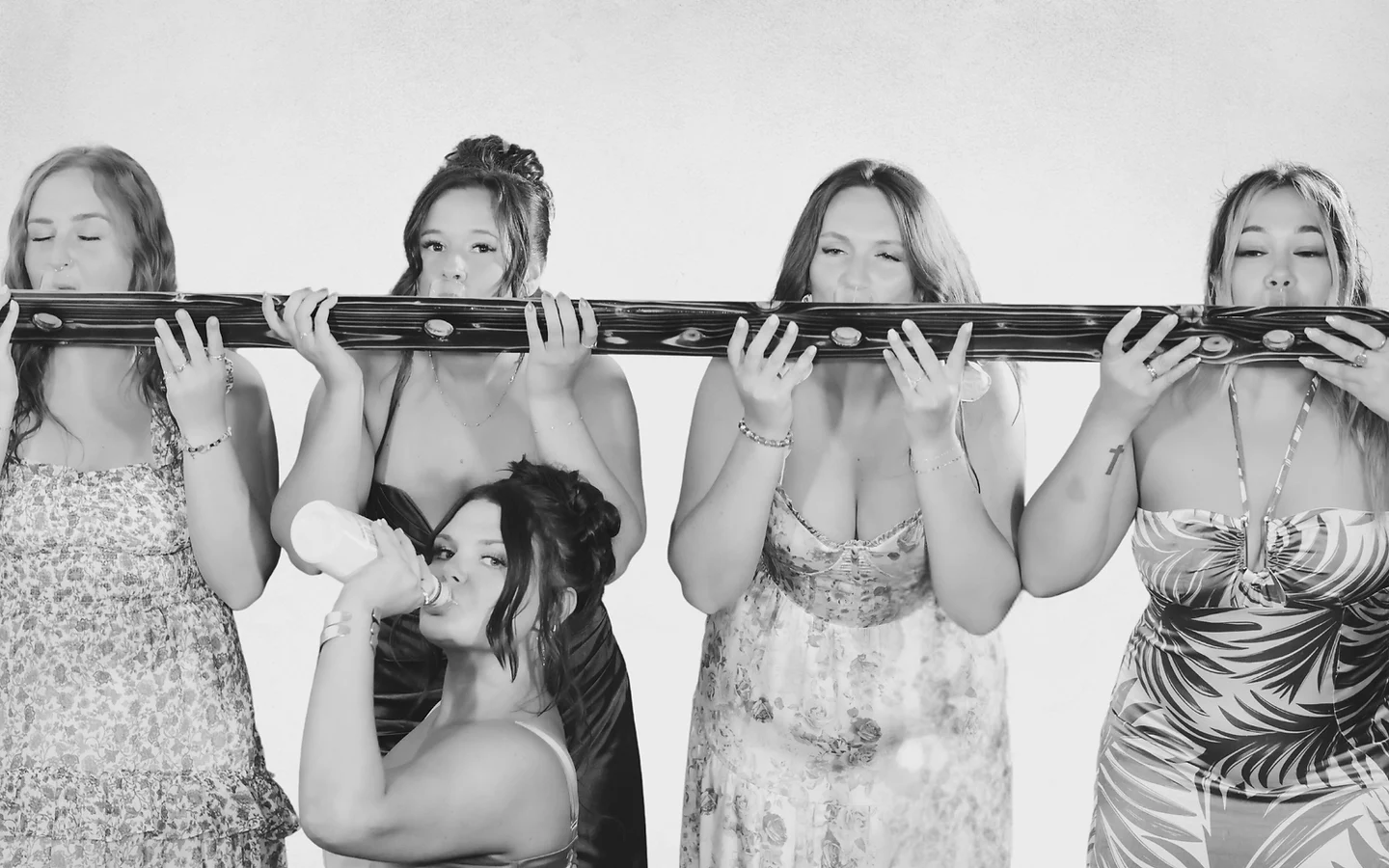 Black and white photo of friends holding a long prop