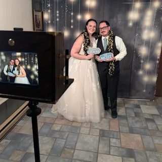 Bride and groom with photo props beside the wedding photo booth