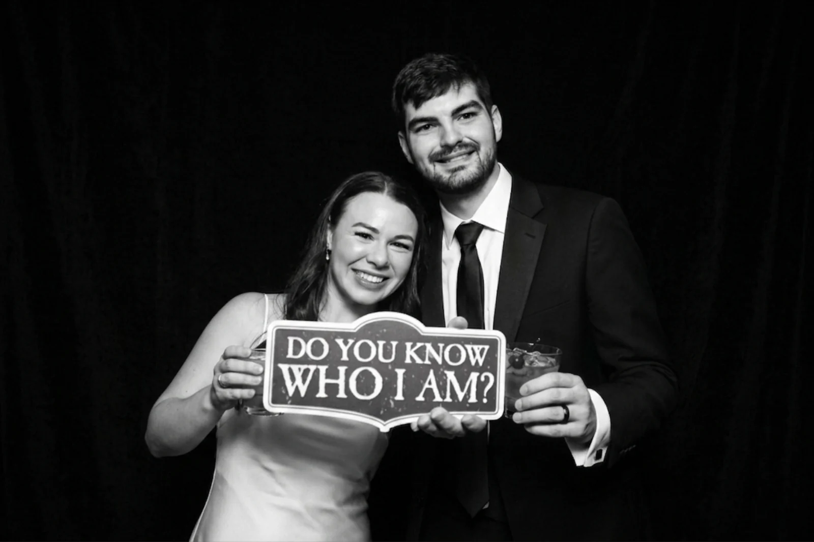 Couple holding a sign against a deep black backdrop