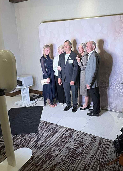 Guests posing in front of a backdrop beside the white iPad booth